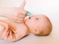 Manos cuidadosas realizan lavado nasal a un bebé.