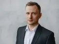 Mężczyzna w garniturze i białej koszuli, idealny przykład, jak zrobić zdjęcie biznesowe w domu.