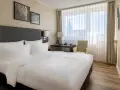 Przytulny pokój w hotelu Radisson Blu Erfurt z białym pościelonym łóżkiem, biurkiem i oknem z widokiem na miasto.