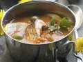 Aromaticzna rosyjska zupa rybna w metalowej misce, z kawałkami ryby, oliwkami, cytryną i natką pietruszki.