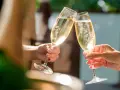 Zwei Hände stoßen mit Gläsern an, gefüllt mit prickelndem alkoholfreiem Sekt. Perfekt für die Schwangerschaft und besondere Anlässe.