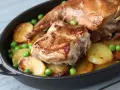 Coniglio arrosto in padella con patate e piselli, un piatto succulento e invitante.