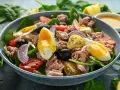 Pyszna keto sałatka z tuńczykiem, jajkiem na miękko, pomidorkami, oliwkami i czerwoną cebulą na świeżym szpinaku.