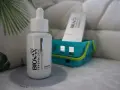 Buteleczka peelingu do skóry głowy L'biotica Bio-Vax Trychologic Advanced Detox stoi na szarej podkładce.