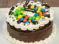 Torta al cioccolato con panna, caramelle colorate e biscotti Oreo, un'esplosione di gusto per torte di compleanno particolari.