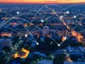 Aerial view of a city at dusk, with glowing lines connecting buildings, symbolizing modern infrastructure and networking.