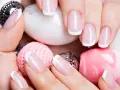 Dłonie z idealnym manicure francuskim, otoczone różowymi i białymi ozdobami.