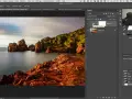 Paysage rocheux au bord de la mer, avec un ciel doux. L'interface Photoshop montre un calque "Vignette de calque", suggérant un effet soleil créé avec Photoshop.
