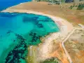 Turkusowe morze obmywa piaszczyste plaże z rzędami parasoli. Widok z lotu ptaka na malownicze wybrzeże.