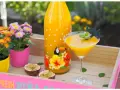 Tropische Früchte und ein leuchtend gelber Drink auf einer rosa Holzschale. Ein ideales Solero Schnaps Rezept ohne Sahne für heiße Tage.