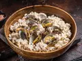 Un tazón de madera lleno de arroz cremoso y almejas frescas, un plato delicioso de arroz con almejas.