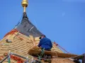 Cieśla dekarz pracuje na dachu, montując drewniane pokrycie.
