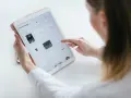 Kobieta tworzy rysowanie na iPadzie, przeglądając swoje prace. Stylus w dłoni sugeruje cyfrowe tworzenie.