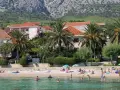 Plaża z palmami, domami i ludźmi kąpiącymi się w morzu.