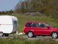 En röd bil drar en vit husvagn, en Kabe Komet, längs en landsväg.