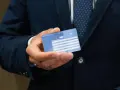 Dłoń trzyma Europejską Kartę Ubezpieczenia Zdrowotnego. Czy EKUZ działa w UK? Tak, karta zapewnia dostęp do opieki medycznej w Wielkiej Brytanii.