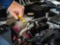 Controllo dei liquidi motore: una mano estrae l'astina per verificare il livello dell'olio.