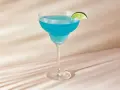 Niebieski drink z ginem, tonikiem i blue curacao, ozdobiony plasterkiem limonki, wygląda orzeźwiająco.