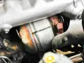 Dettaglio del sistema di scarico di un'auto, con il filtro antiparticolato (FAP) visibile. Togliere il FAP vantaggi: meno intasamenti, migliore fluidità dei gas.