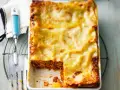 Eine frisch gebackene, italienische Lasagne in einer Auflaufform, mit einer goldbraunen Käseschicht und einem Stück herausgenommen.