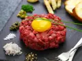 Tartare di manzo fresca e succulenta, con tuorlo d'uovo, capperi, cipolla, sale, pepe e crostini.
