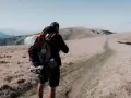 Uomo con zaino da trekking su un sentiero di montagna.