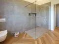 Bagno moderno con doccia walk-in, vaso sospeso e finiture in legno. Il significato di doccia walk-in è uno spazio aperto e accessibile.