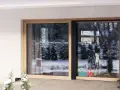 Duże okno HST z drewnianą ramą, przez które widać zimowy ogród i zabawki.