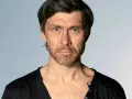 Marcin Czarnik, aktor o intensywnym spojrzeniu i niebieskich oczach, w czarnej koszulce.
