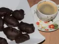 Czekoladowe śliwki z nalewki na talerzu, obok filiżanka kawy. Idealne, gdy zastanawiasz się, co zrobić ze śliwkami z nalewki.