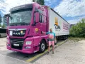 Mężczyzna obok różowej ciężarówki MAN. Na naczepie napis "JA ZDAM SZKOŁA JAZDY". Dowiedz się, ile kosztuje prawo jazdy C.