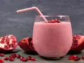 Orzeźwiający drink z granatem, udekorowany nasionami i kawałkami owocu. Idealny na letnie popołudnie.