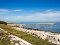 Sentiero in pietra e mare calmo con barche. Per capire come arrivare a Pellestrina da Fusina, immagina di percorrere questa costa.