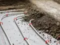 Instalacja ogrzewania podłogowego z rurkami mocowanymi do folii, gotowa do zalania jastrychem.