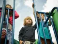Chłopiec z blond lokami, idealna fryzura dla chłopca 3 latka, na placu zabaw z innymi dziećmi.