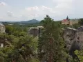 Widok na zamek Hrubá Skála otoczony skalnymi formacjami i lasem.