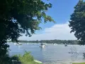 Boote auf dem Glindower See unter blauem Himmel, umgeben von grünen Bäumen. Ein sonniger Tag am Wasser.