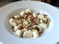Pyszna keto kolacja z twarogiem w formie kluseczek, posypana chrupiącym boczkiem i cebulką.