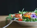 En vacker sallad med lax, tomater och ätbara blommor. Perfekt för att deffa mat och njuta av en hälsosam måltid.