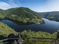 Vue panoramique des gorges de la Truyère, un lac paisible reflétant les collines verdoyantes. Idéal pour la randonnée.