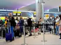 Kolejka do odprawy na lotnisku, przypominająca terenową delegaturę paszportową w Bielsku-Białej. Ludzie z bagażami czekają na swoją kolej.