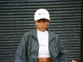Kobieta w białej czapce z logo Karl Kani i kurtce tej marki. To kultowa marka streetwearowa.