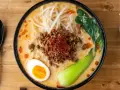 Miseczka ramenu tantanmen z mielonym mięsem, jajkiem, kiełkami i warzywami.