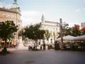 Spacer z kawiarnianymi stolikami i ludźmi, uchwycony aparatem Kodak M35.