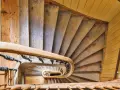Widok z góry na kręcone schody drewniane, idealne do czyszczenia schodów drewnianych. Widać ozdobną balustradę i drewniane stopnie.