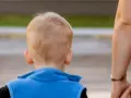 Wskazówki, jak rozmawiać z dzieckiem z aspergerem. Dłoń dorosłego prowadzi dziecko w niebieskiej kamizelce.