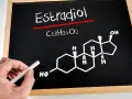 Estradiol co to za badanie? Na tablicy wzór chemiczny estradiolu (C18H24O2) i jego struktura. Ręka z kredą.