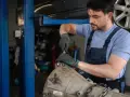 Mechanik w warsztacie wykonuje naprawę hybryd, pracując nad skrzynią biegów.