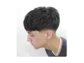 Joven con corte de pelo moderno, un low fade hombre con la parte superior texturizada y flequillo recto.