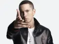 Eminem w czarnej skórzanej kurtce i białej koszulce, z ręką wyciągniętą w stronę widza.